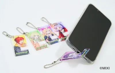アニメキャラクターが描かれた複数のアクリルキーホルダーと、キーホルダーをスタンドとして利用しているスマートフォン