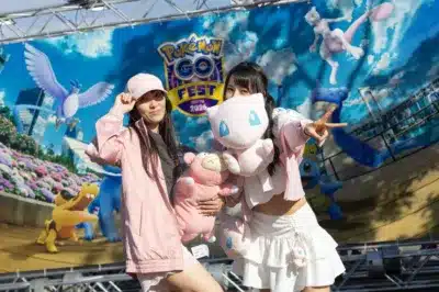 イベントバナーの前でポケモンぬいぐるみを持つ女性たち