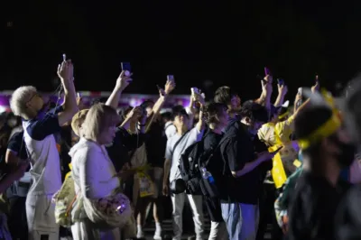 夜のイベント会場でスマートフォンを掲げる群衆