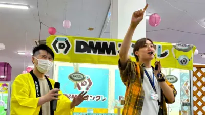 DMMオンクレのイベントで、二人の男性がマイクを持って盛り上げている様子